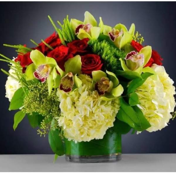 Red roses and pale green orchids in a glass vase