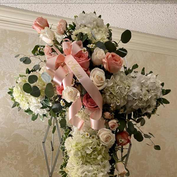 Large cross-shaped floral arrangement with pink and white roses