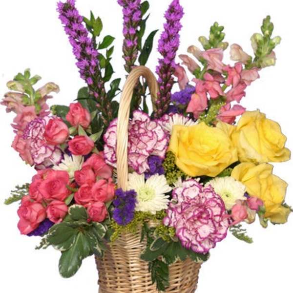 Wicker basket of yellow roses, pink spray roses, purple spikes, and mixed blooms in bright colors