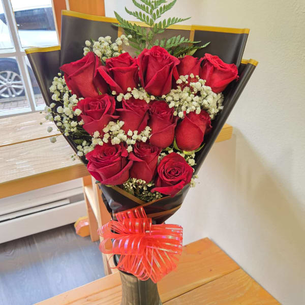 Bouquet of red roses with white baby's breath in black wrap and a red ribbon