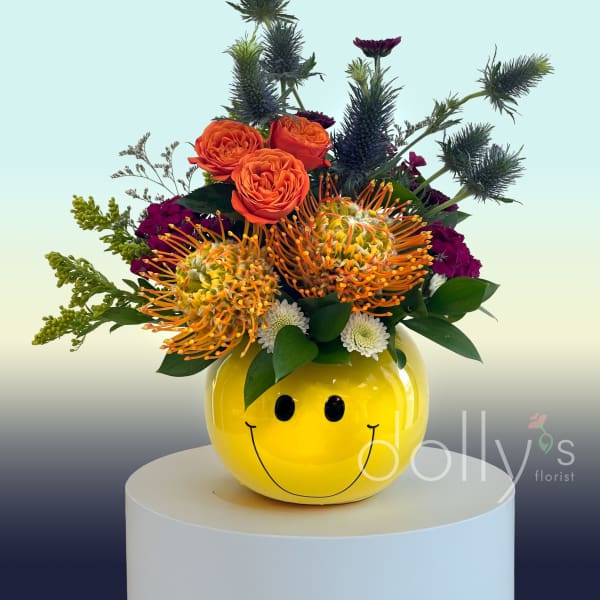 Bright mixed bouquet in a yellow smiley-face vase