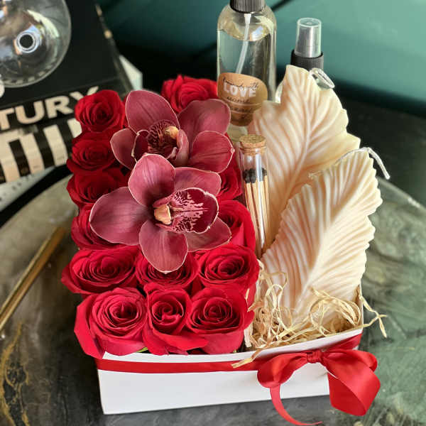 Red roses and pink orchids arranged with candles in a white gift box