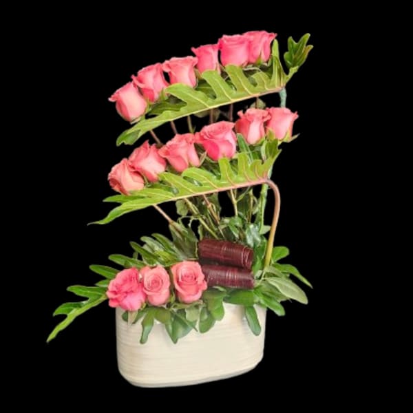 Pink roses arranged in a white basket with layered greenery