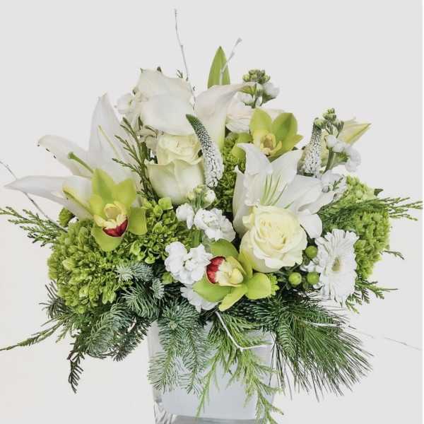White and green floral arrangement in a clear square vase