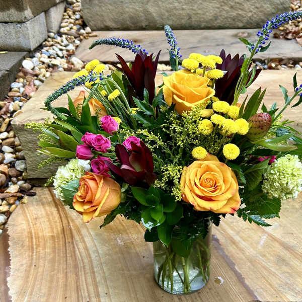 Mixed bouquet of yellow and orange roses in a clear glass vase