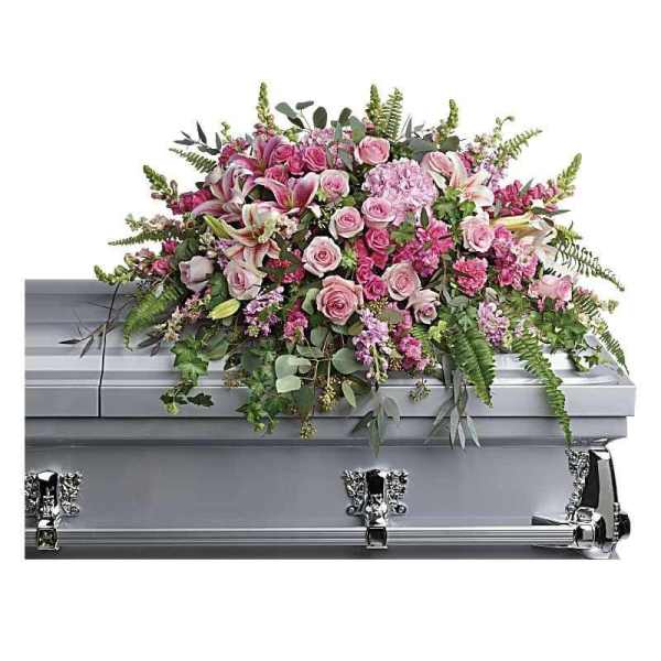 Pink floral casket spray with roses and lilies on a silver casket