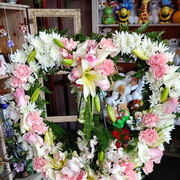 Heart-shaped floral wreath on a stand with pink and white flowers