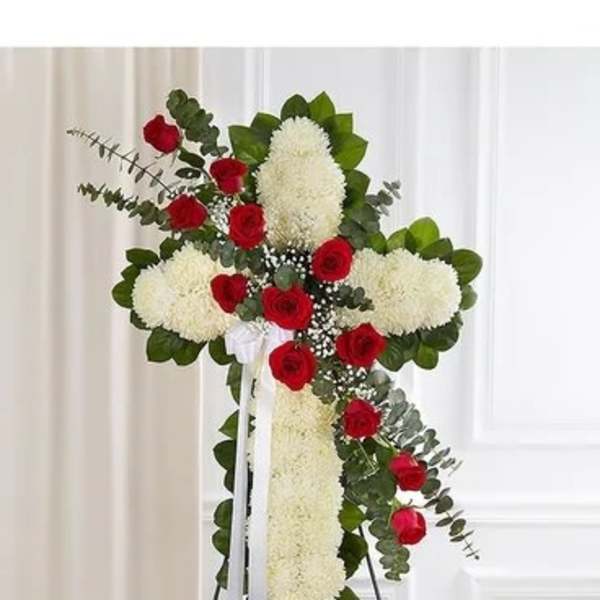 Standing floral cross with red roses and white blooms on an easel