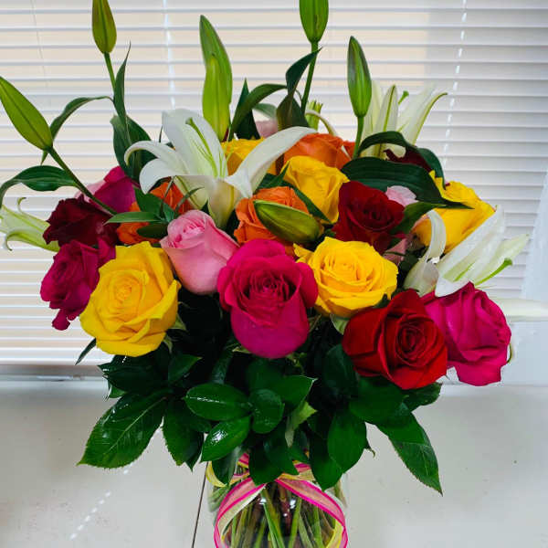 Bouquet of multicolored roses and white lilies in a glass vase