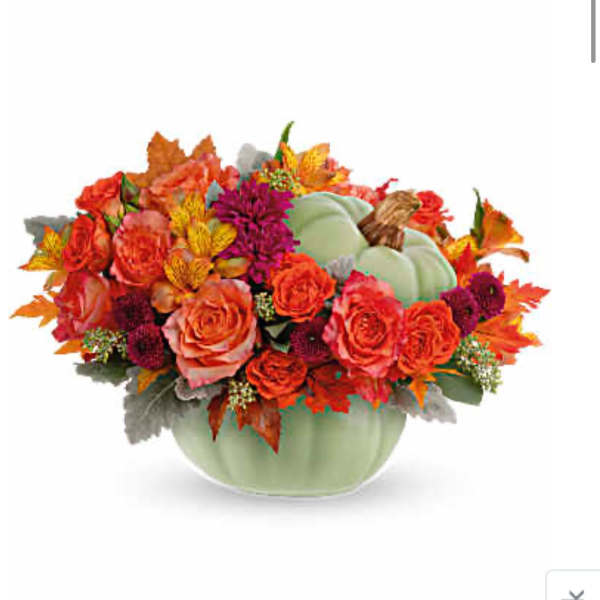Autumn bouquet of orange roses and mixed flowers in a pale green pumpkin vase