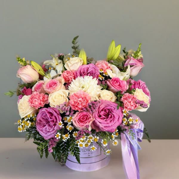 Mixed pink and cream flower arrangement in a lavender hat box with ribbon