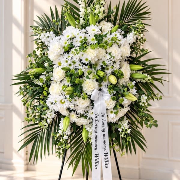 White funeral standing spray with lilies, roses, and daisies on an easel