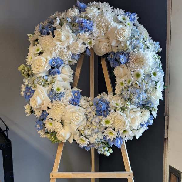 White and blue floral wreath on a wooden easel