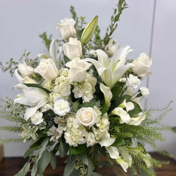 White roses, lilies, and calla lilies in a glass vase