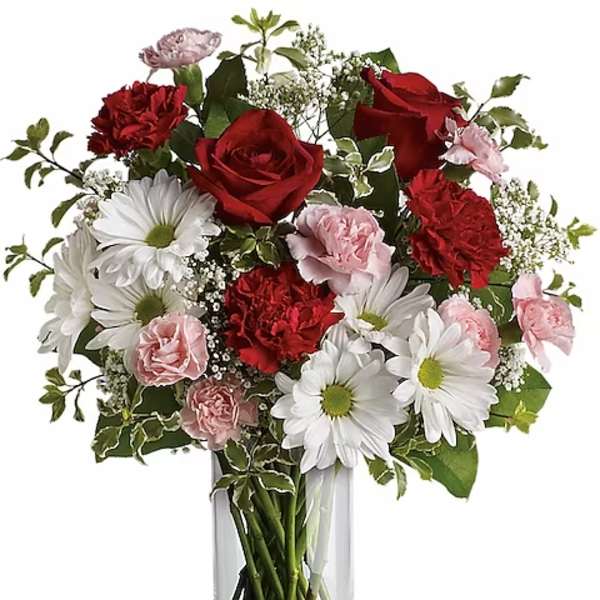 Bouquet of red roses, white daisies, and pink carnations in a clear glass vase