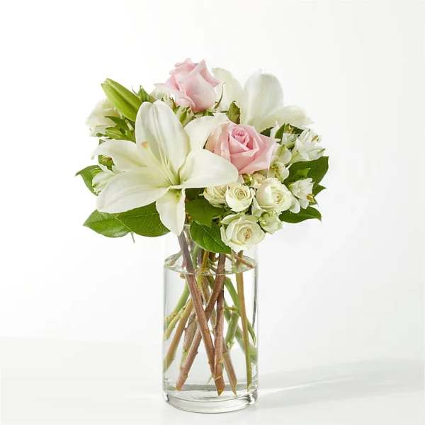 Pink roses and white lilies arranged in a clear glass vase