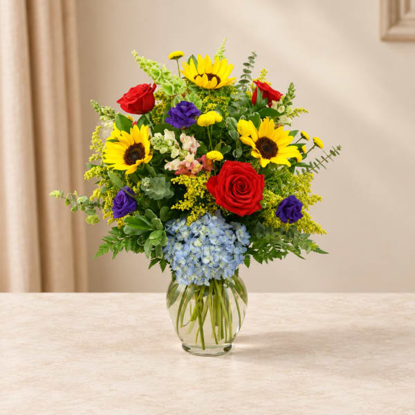 Colorful bouquet of sunflowers, roses, and hydrangea in a glass vase
