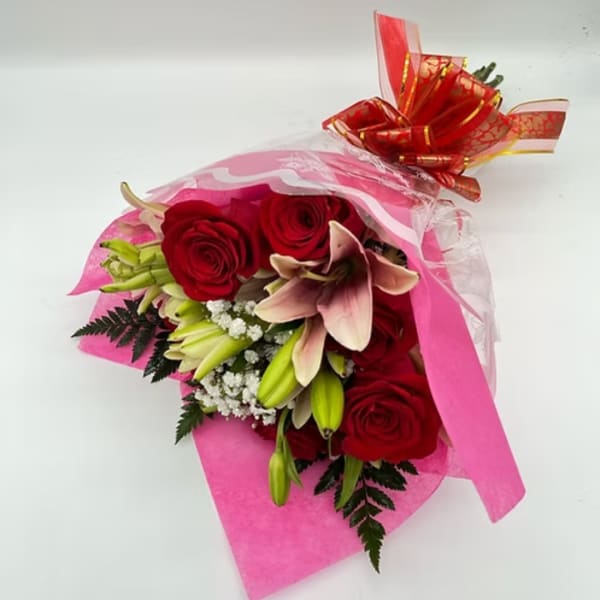 Bouquet of red roses and pink lilies wrapped in pink paper