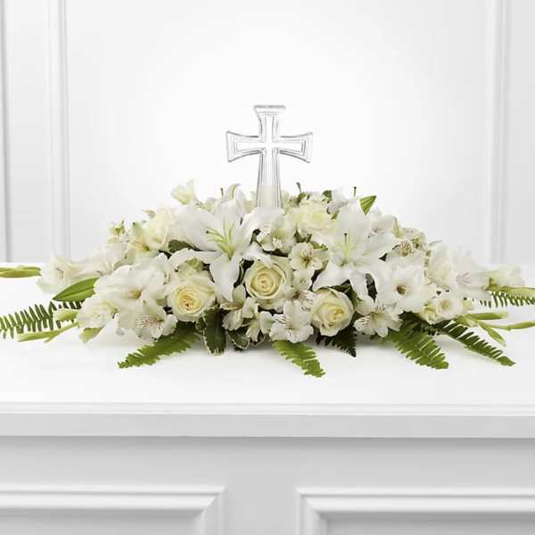 White floral casket spray with a clear cross centerpiece