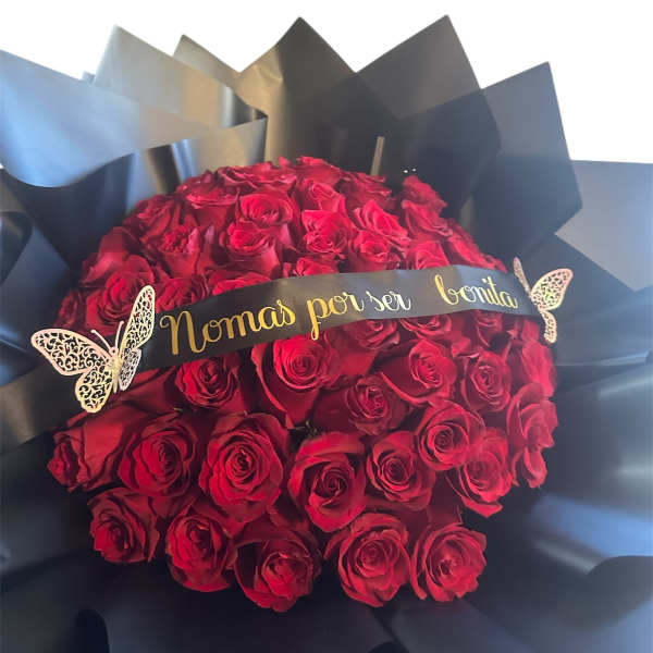 Bouquet of red roses wrapped in black paper with a gold ribbon