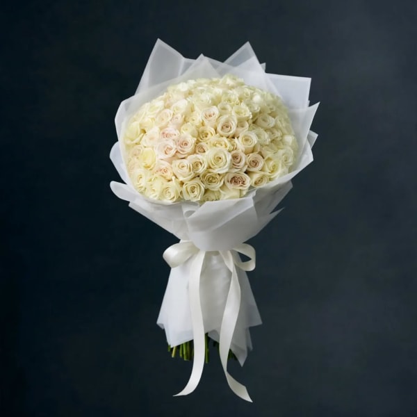 Bouquet of cream and pale blush roses wrapped in white paper