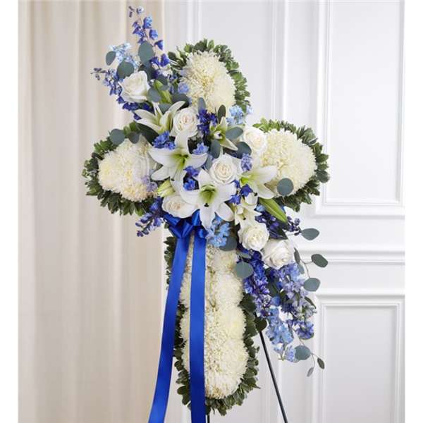 White floral cross arrangement with blue ribbon and blue accents