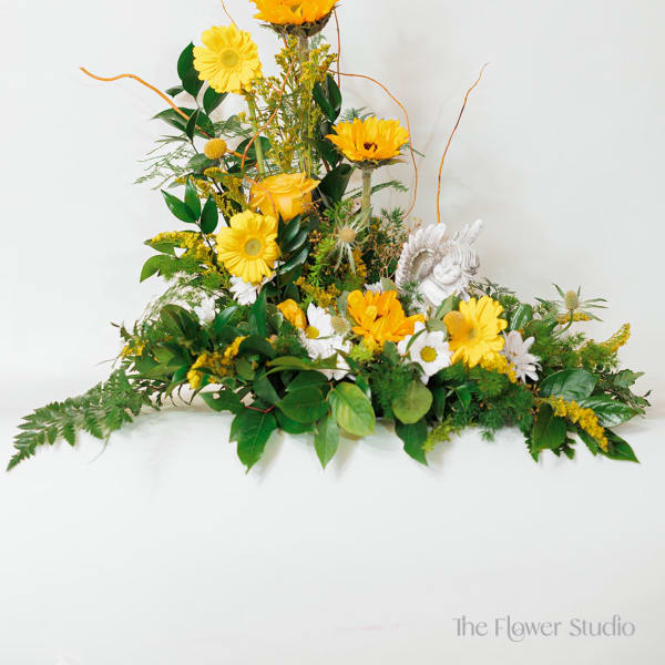Yellow and white floral arrangement with a small angel figurine