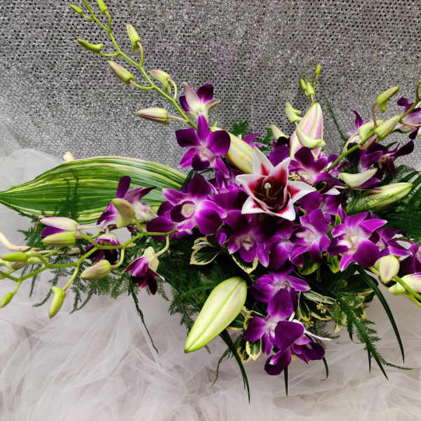 Purple orchid arrangement with white lilies and green foliage