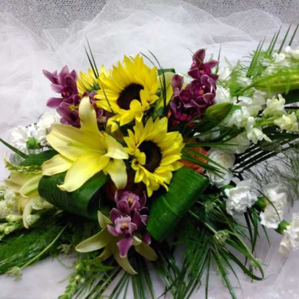 Bouquet with sunflowers, lilies, and purple orchids on white fabric