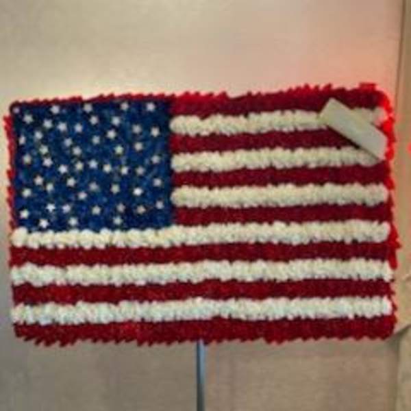 Floral arrangement shaped like the U.S. flag on a stand