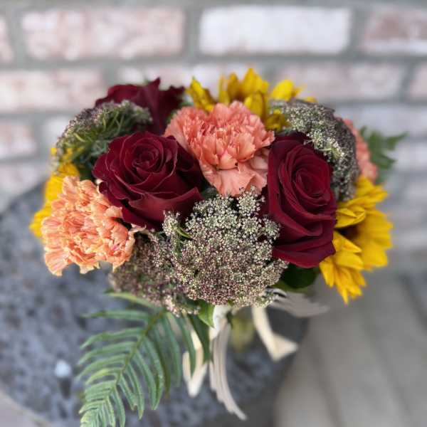 Bouquet of burgundy roses, peach carnations, and yellow flowers