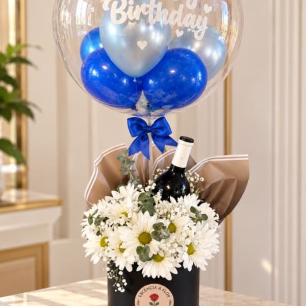 White daisies in a black gift box with a birthday balloon and wine bottle