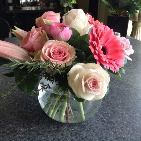 Pink and cream flower arrangement in a glass bowl vase