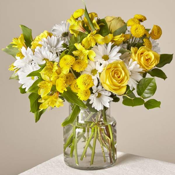 Yellow roses and white daisies in a clear glass vase