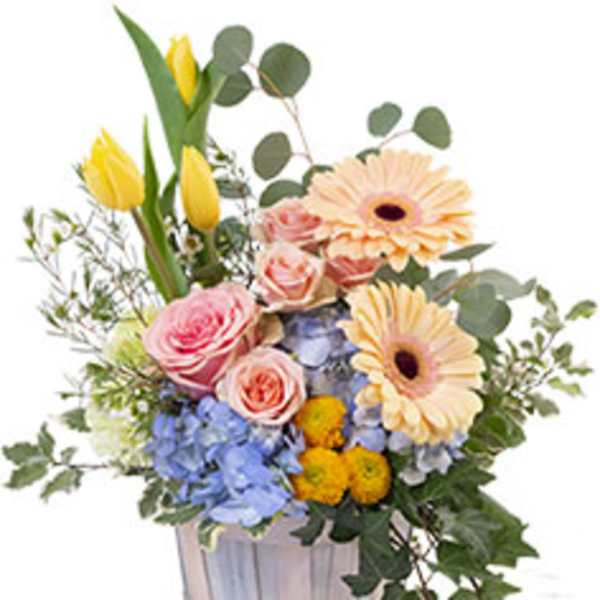 Mixed bouquet in a silver container with pink roses, yellow tulips, and peach daisies