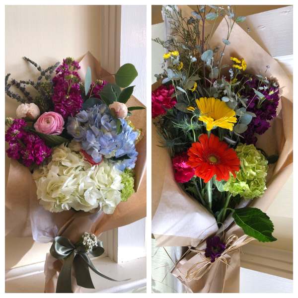 Two wrapped bouquets with mixed flowers in pink, blue, yellow, and purple.