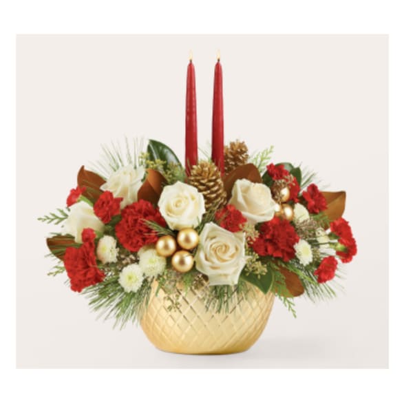 Red and white floral arrangement in a gold vase with two red candles