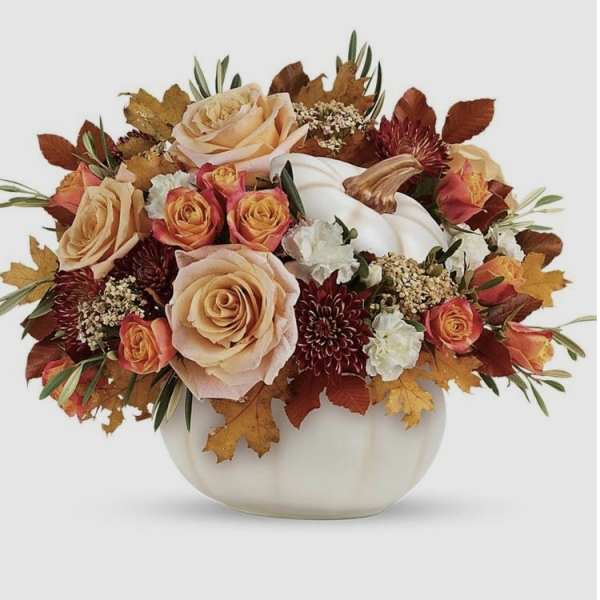 Autumn floral arrangement with roses and a white pumpkin in a white vase