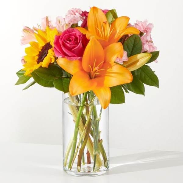 Bouquet of orange lilies, a pink rose, and a sunflower in a glass vase