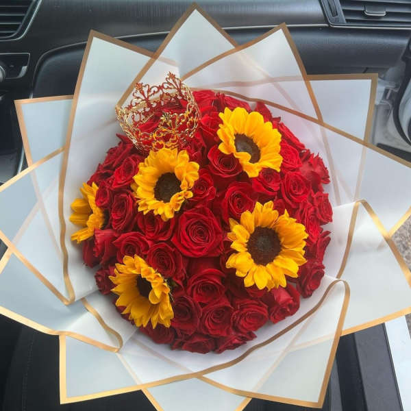 Bouquet of red roses and yellow sunflowers wrapped in white paper