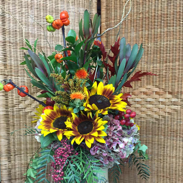 Sunflower arrangement in a green vase with berries and autumn foliage