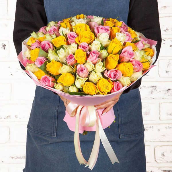 Bouquet of pink, yellow, and white roses wrapped in pink paper
