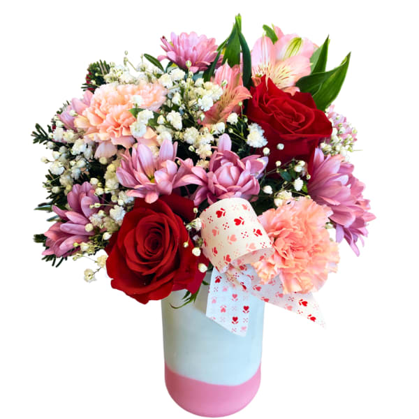 Bouquet of red roses, pink carnations, and purple daisies in a pastel vase