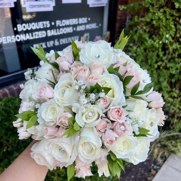 Round bouquet of white and pale pink roses with small white filler flowers