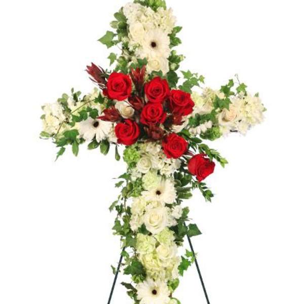 Standing floral cross with red roses and white flowers on an easel