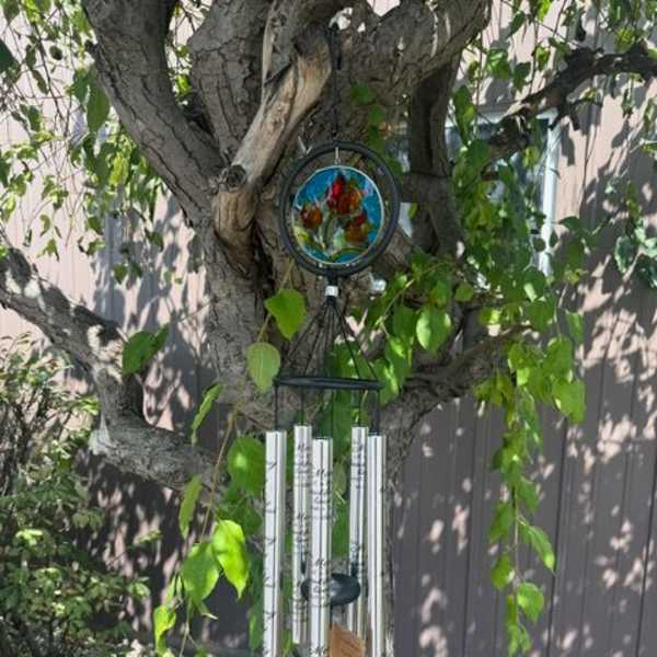 Wind chime hanging from a tree branch with stained-glass accents
