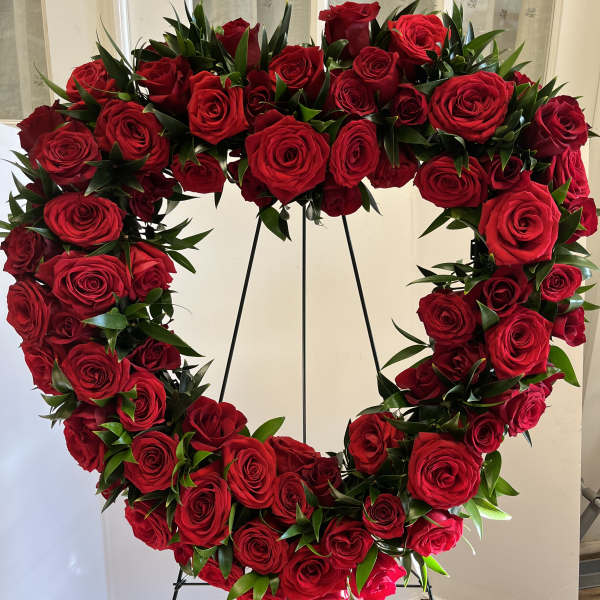 Heart-shaped wreath of red roses on a black stand