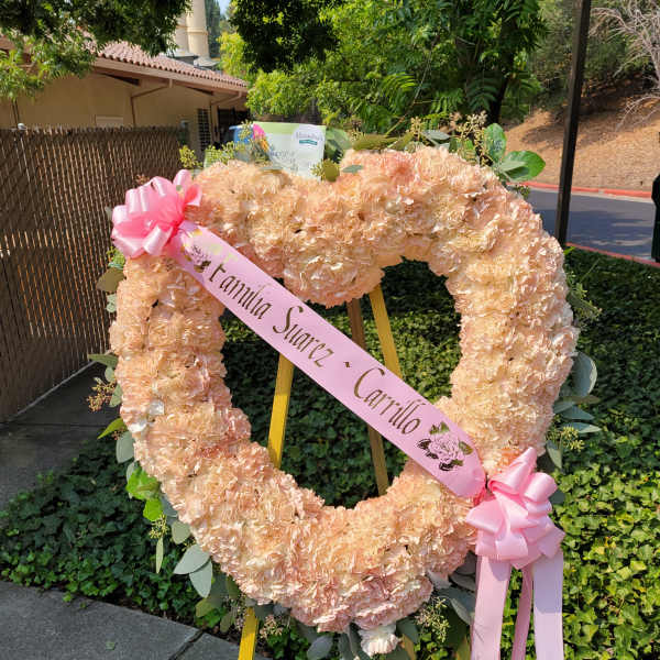 Peach floral heart wreath on an easel with pink ribbons
