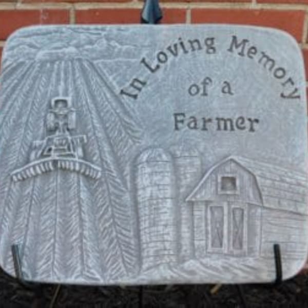 Gray memorial plaque with a farm scene and the words 'In Loving Memory of a Farmer'
