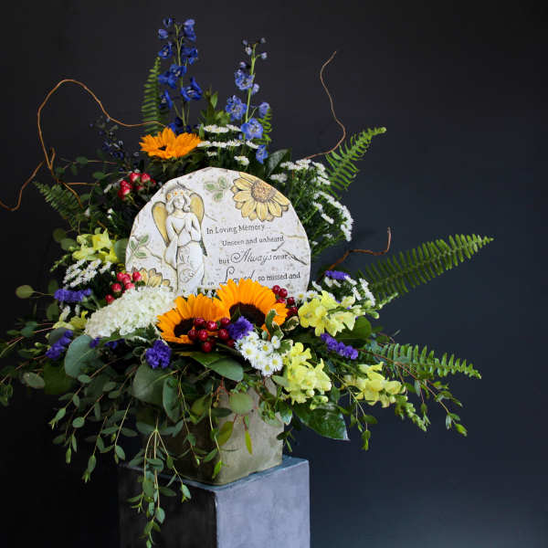Sympathy floral arrangement with a memorial plaque and mixed flowers